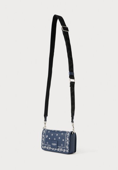 Kleine rechthoekige crossbodytas in donkerblauw met bloemmotieven, structuurleer en een contrasterende zwarte riem met logotekst.