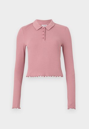 Hosszúujjú, cropped polo póló bordás, puha rózsaszín anyagból. Gallérral és négy gombos gombolással, valamint fodros aljjal rendelkezik.