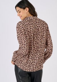 Leopard print blouse in tan, featuring long sleeves and a relaxed fit. Soft, smooth fabric with a lightweight feel and subtle sheen.