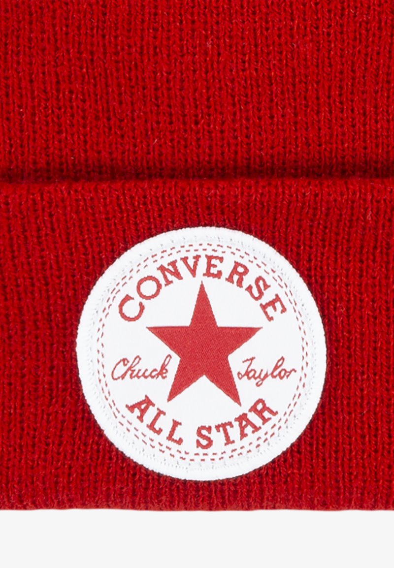 Gorro de lana rojo con un parche blanco circular que tiene una estrella roja y el texto "CONVERSE ALL STAR" y "Chuck Taylor" en una fuente clásica.