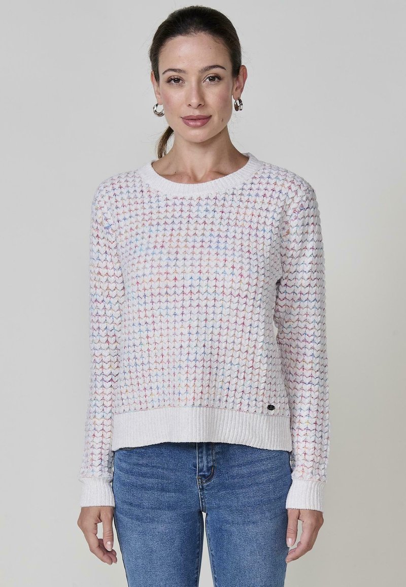 Sweter w dzianinę w jasnoróżowym kolorze z wielokolorowymi drobinkami, okrągłym dekoltem, ściągaczami na rękawach i końcach, z małym akcentem logo na dole.