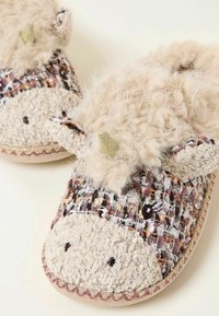 Slippers with a textured, woven fabric in earth tones, featuring a fuzzy beige upper and small decorative ears. Round, flat toe design.