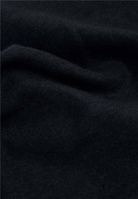 Tejido de lana suave y texturizada en negro profundo, con pliegues suaves y una apariencia rica, que resalta sus cualidades cálidas y acogedoras.