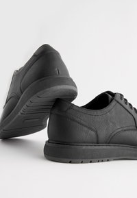 Chaussures en cuir noir avec une finition texturée, bout arrondi et semelle en caoutchouc. Design à lacets avec des accents de couture pour plus de détails.