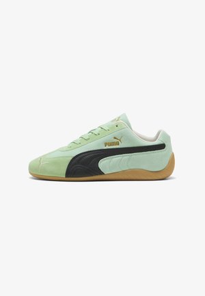Scarpa da ginnastica Puma verde menta con striscia laterale nera, suola in gomma, logo Puma dorato e design con lacci, vista dal lato esterno.