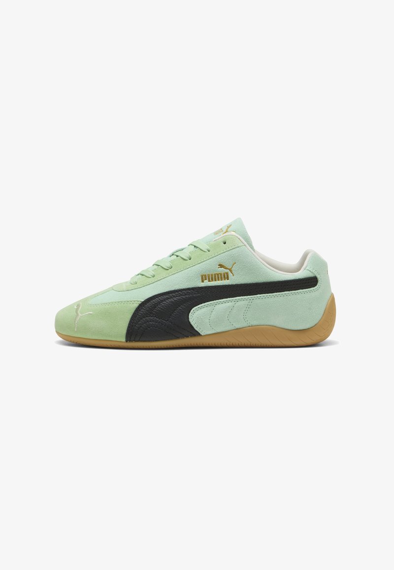 Mintgrüner Puma-Sneaker mit schwarzem Seitenstreifen, brauner Gummisohle, goldenem Puma-Logo und Schnürdesign, von der Außenseite betrachtet.