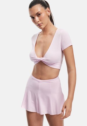 Lyserød crop top med dyb V-udskæring og knudedetalje, der er parret med en matchende udvidet mini-nederdel. Glat, strækbart stof.
