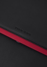 Sort faux lædermappe med en livlig rød kant langs kanten. "PIER ONE" er præget i sort på den forreste overflade.