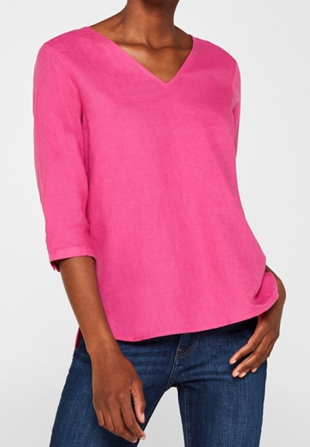 Blusa di lino rosa con scollo a V, maniche a tre quarti e taglio rilassato. Il tessuto appare leggero e ha una texture liscia.
