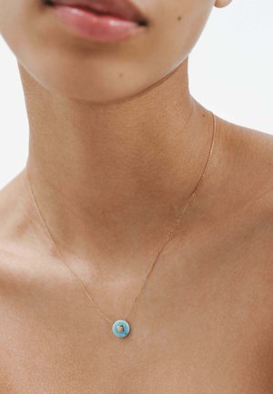 Collar de cadena de oro con un colgante circular de turquesa y un pequeño detalle cuadrado. Textura suave, diseño minimalista.
