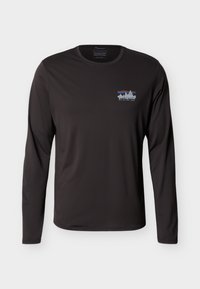 Μαύρο μακρυμάνικο πουκάμισο Patagonia με μικρό πολύχρωμο λογότυπο βουνού και το κείμενο «Save Our Home Planet» στο αριστερό στήθος.