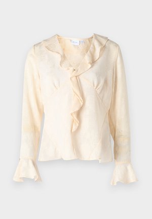 Kreemivärvi pluus tekstuurse lillemustriga, volangkaeluse ja laienevate varrukatega. Omab mähise disaini ja peent sära.