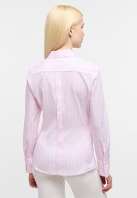 Camicia button-up rosa chiaro con strisce bianche verticali, maniche lunghe e colletto classico. Tessuto liscio con vestibilità su misura.