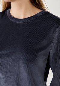 Top a maniche lunghe in maglina a coste blu navy, con scollatura rotonda e texture liscia, caratterizzato da linee orizzontali che creano un motivo sottile.