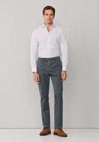 Witte longsleeve shirt met dunne strepen, grijze op maat gemaakte broek en bruine leren schoenen. De outfit heeft een klassieke kraag en een vlakke voorkant.