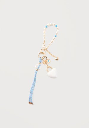 Võtmehoidja kuldsete rõngaste, valgete helmeste, siniste helmestega, valge südamekujulise lukuga ripatsi, sinise tutt ja väikeste kuldsete ning siniste kurjade silmadega ripatsitega.