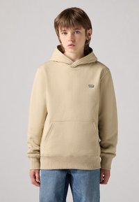 Felpa con cappuccio beige, dotata di tasca a canguro e polsini a costine. Piccolo patch con logo sul petto, realizzata in morbido tessuto testurizzato.