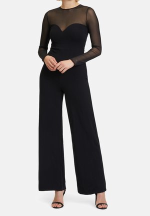 Černý overal s dlouhými průsvitnými rukávy a výstřihem ve tvaru srdce, s širokými nohavicemi a hladkým povrchem. Doplněno otevřenými lodičkami.