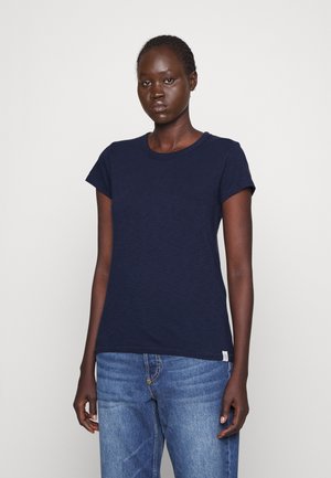 Navy blue short-sleeve T-shirt made of cotton with a round neckline and subtle texture. Worn with light blue jeans, minimal detailing present.