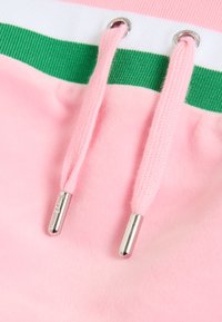 Krupan plan ružičastog materijala dukserice s rebrastim obrubom prugastim u zeleno i bijelo te ružičastim vrpcama za vezivanje sa srebrnim metalnim vrhovima.