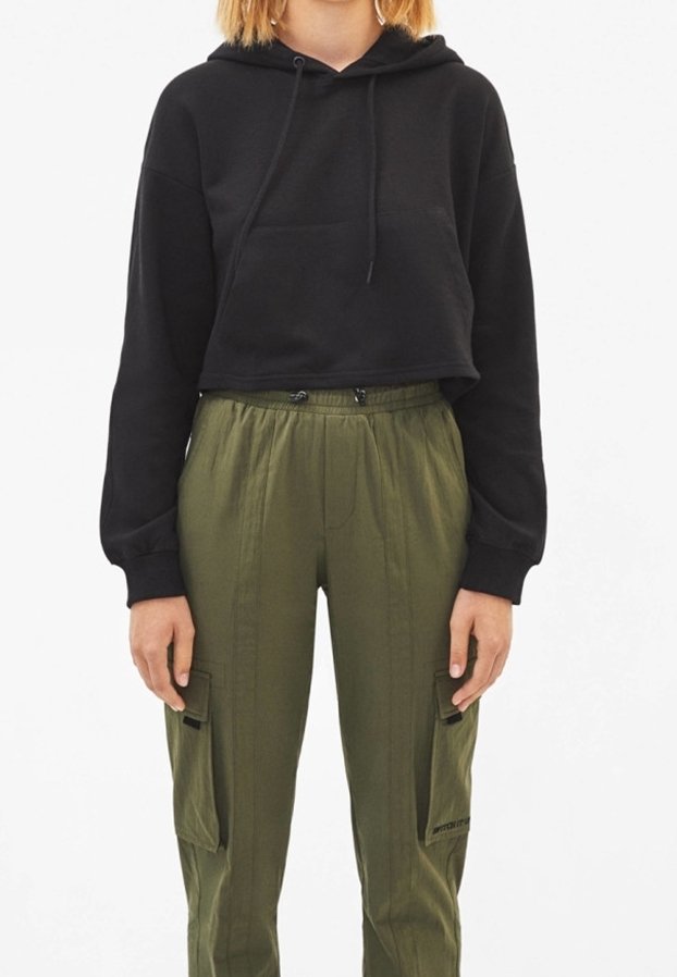 Svart avkortad hoodie med snoddar, kombinerad med olivgröna cargobyxor med sidofickor och resårmidja.