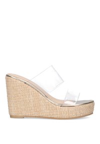 Sandalias de cuña transparentes con una base de paja trenzada, borde metálico y dos cintas transparentes en la parte superior.