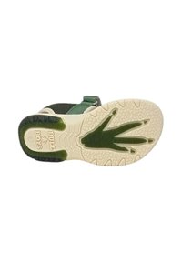 Scarpa verde e nera con una suola in gomma texturizzata che presenta un motivo stampato a forma di mano. Cinturino regolabile e parte superiore simile a rete per la traspirabilità.