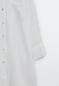 Witte linnen overhemd met een button-down ontwerp, voorzien van een enkele borstzak, een kraag en opgerolde mouwen met knoopaccenten.