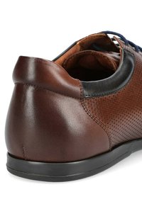 Brązowy skórzany but z perforowanym wzorem, czarnymi akcentami, zaokrąglonym obcasem i gumową podeszwą. Posiada niebieskie sznurowadła i smukłą sylwetkę.