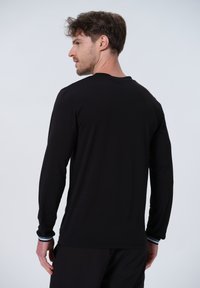 Langärmliges schwarzes Hemd mit einem Rundhalsausschnitt und schlanker Passform. Verfügt über kontrastierende gestreifte Bündchen und einen glatten Baumwollmischgewebe.