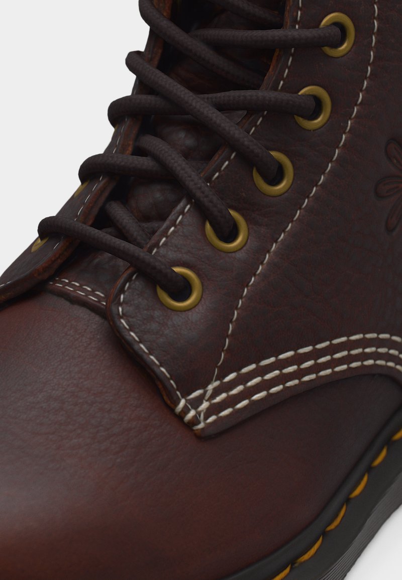 Nahaufnahme eines braunen Lederstiefels mit dunklen Schnürsenkeln, die durch Messingösen gezogen sind, und weißen doppelten Nähten entlang der Nähte.