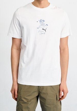 Maglietta bianca in cotone con grafica blu di un giocatore e testo "Puma Sports". Girocollo e maniche corte. Vestibilità casual.