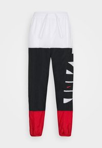 Nike Laufhose mit weißem Bund, schwarzem Mittelteil mit fettem weißen "NIKE"-Schriftzug und rohem Swoosh sowie roten Unterschenkeln.