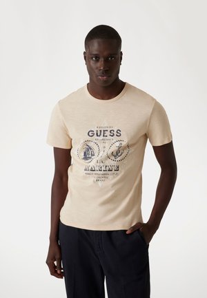 Light beige crew neck t-shirt with a graphic print featuring a sailing ship and anchor. Made of a soft material, short sleeves, fitted style.
