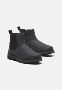 Botas de tobillo de cuero azul marino oscuro con paneles laterales elásticos, punta redondeada y suela de goma texturizada con profundos surcos para un buen agarre.