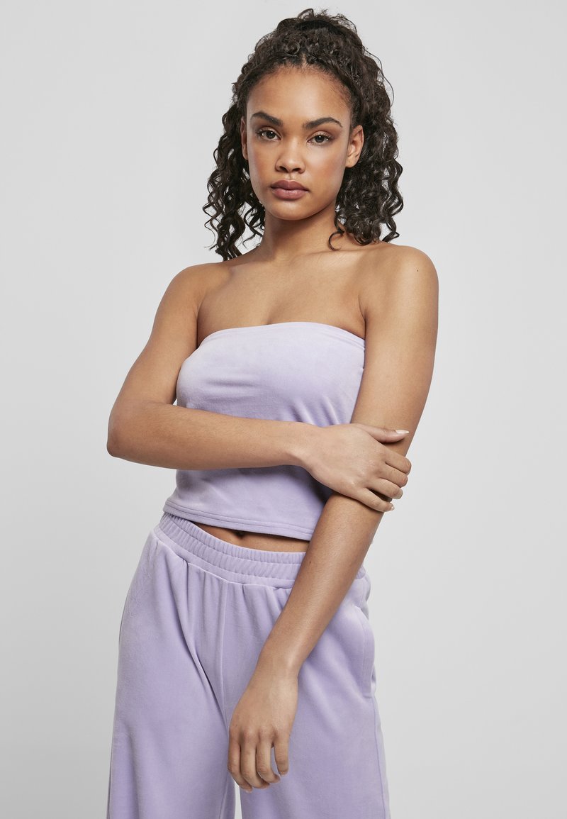 Mīksta lilā strapless blūze, izgatavota no pūkaina materiāla, kombinēta ar atbilstošām brīvām sporta biksēm ar elastīgu jostu. Minimalistiska dizaina.
