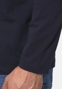 Navyblaues Langarmhemd aus Baumwolle mit schmaler Passform, glatter Textur und einer genähten Saumnaht am Ärmelabschluss.