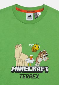 Πράσινο βαμβακερό μπλουζάκι με ψηφιακούς χαρακτήρες Minecraft: μια μέλισσα, μια κότα, ένα λάμα και ένα σκύλο. Περιλαμβάνει το κείμενο "Minecraft Terrex".