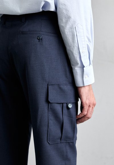 Pantalones cargo azul marino hechos de tela texturizada; cuentan con bolsillos laterales con cierre de botón y una cinturilla suave.