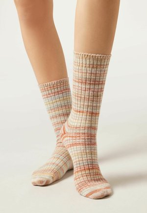 Chaussettes montantes en matériau doux, ornées d'un motif écossais multicolore dans des rayures pêche, beige et bleu clair, avec des bords côtelés.