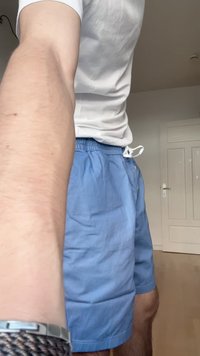 Pantaloni corti azzurri realizzati in un tessuto dalla superficie liscia, dotati di una cintura elasticizzata con cordoncino e tasche laterali.