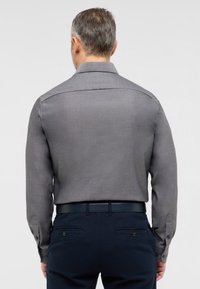 Grijze langemouwen shirt met een gladde textuur en knoopmanchetten, gedragen met marineblauwe broek. Ontwerp heeft een klassieke kraag en een getailleerde pasvorm.