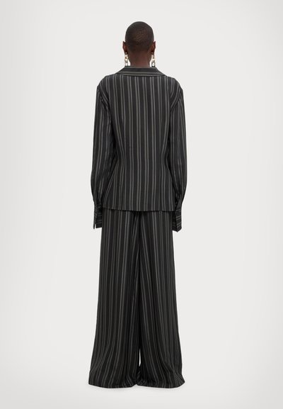 Black and grey striped suit featuring a blazer with a collar and wide-leg pants, made from a smooth fabric with a relaxed fit.