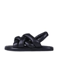 Sandalias de cuero negro con un diseño anudado, suela plana y textura suave. Presentan una estética minimalista y parte trasera abierta para facilitar su uso.