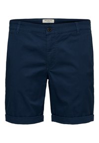 Marinblå shorts i bomull med platt front, vikta knän, en enkel knappstängning och bälteshällor. Inga synliga mönster eller dekorationer.
