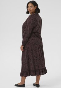 Robe à manches longues, à motifs floraux sombres avec un ourlet à volants. Fabriquée en tissu léger, elle présente une coupe décontractée et de subtils volants pour ajouter de la texture.