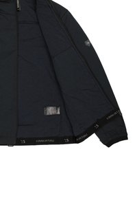 Donkerblauwe jas met een ritssluiting aan de voorkant, voorzien van een glad interieur, elastische manchetten en een logoband aan de onderrand. Inclusief binnenzak.