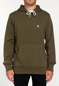 Sweat à capuche vert olive en tissu doux avec une poche kangourou, un cordon blanc et un petit logo sur la poitrine. Coupe standard, manches longues.