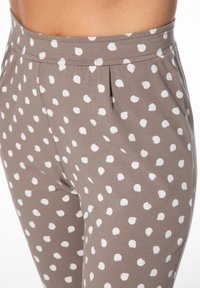 Grau melierte Leggings mit einem weißen Punktmuster. Der Bund ist elastisch und verfügt über dezente Falten für ein zusätzliches Design.