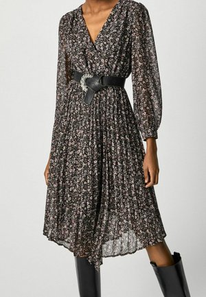 Abito floreale nero con design plissettato, dotato di maniche lunghe in chiffon, scollatura a V e una larga cintura nera con dettaglio fibbia in argento.